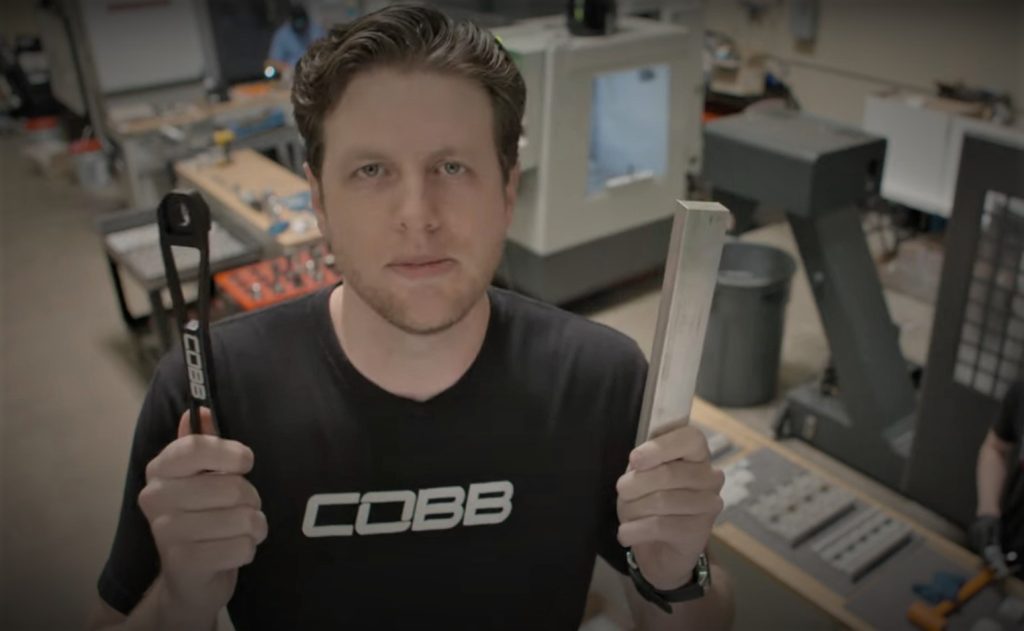 man holding a billet block and part in a factory