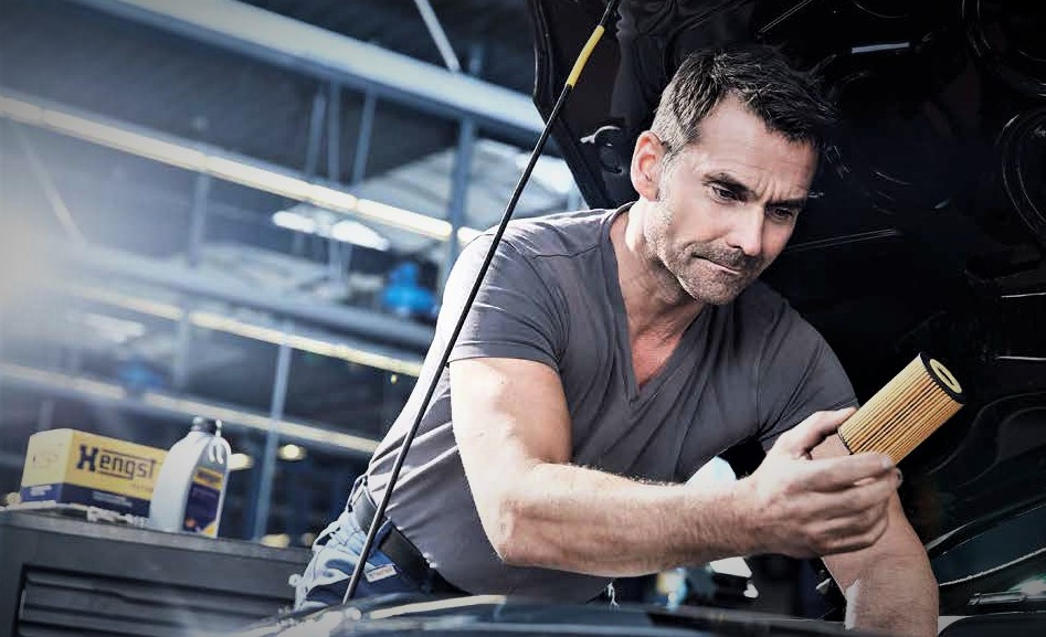 Man holding a hengst filter over an engine bay