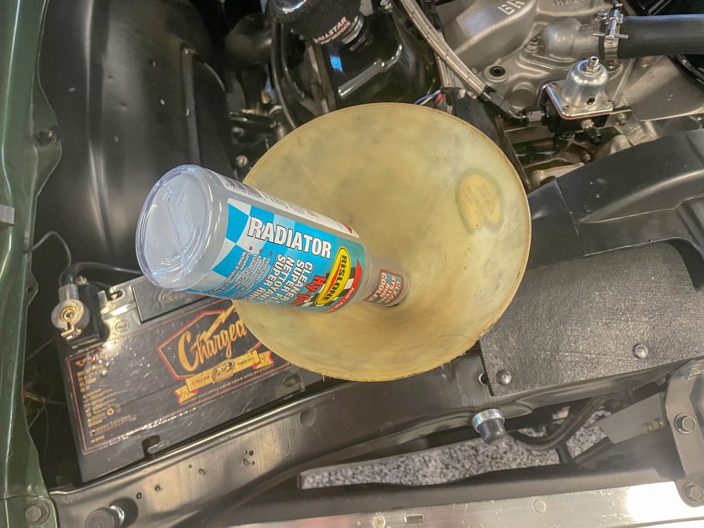 radiator cleaner flush getting poured into a funnel