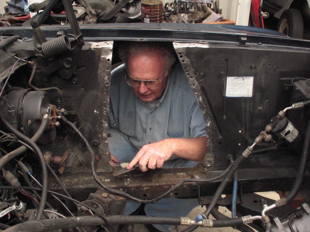 Man working inside a vintage mustang fender