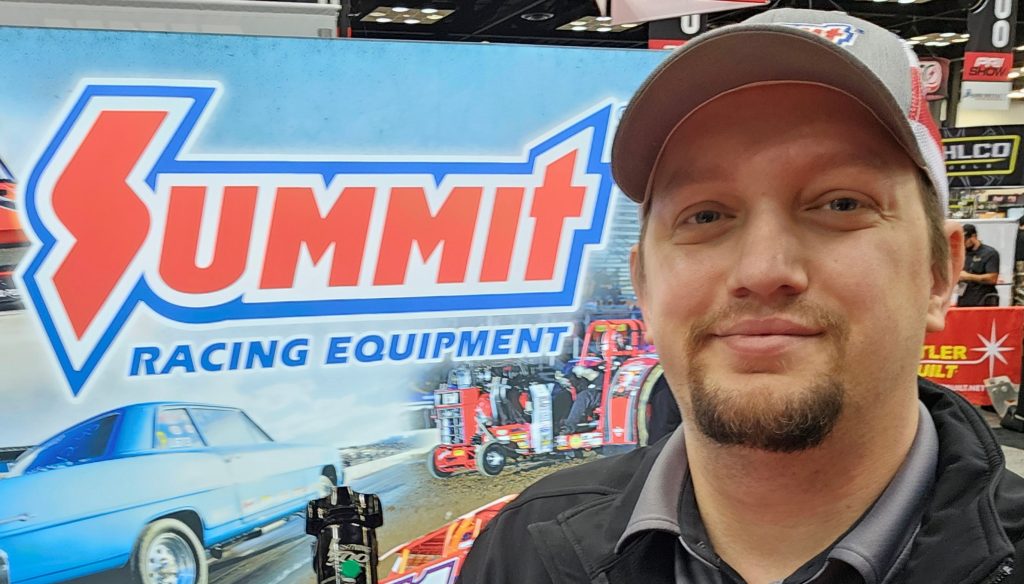 man standing near summit racing logo
