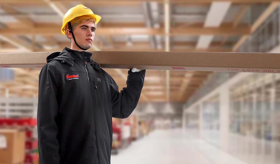 man in a jacket carrying a board in a warehouse