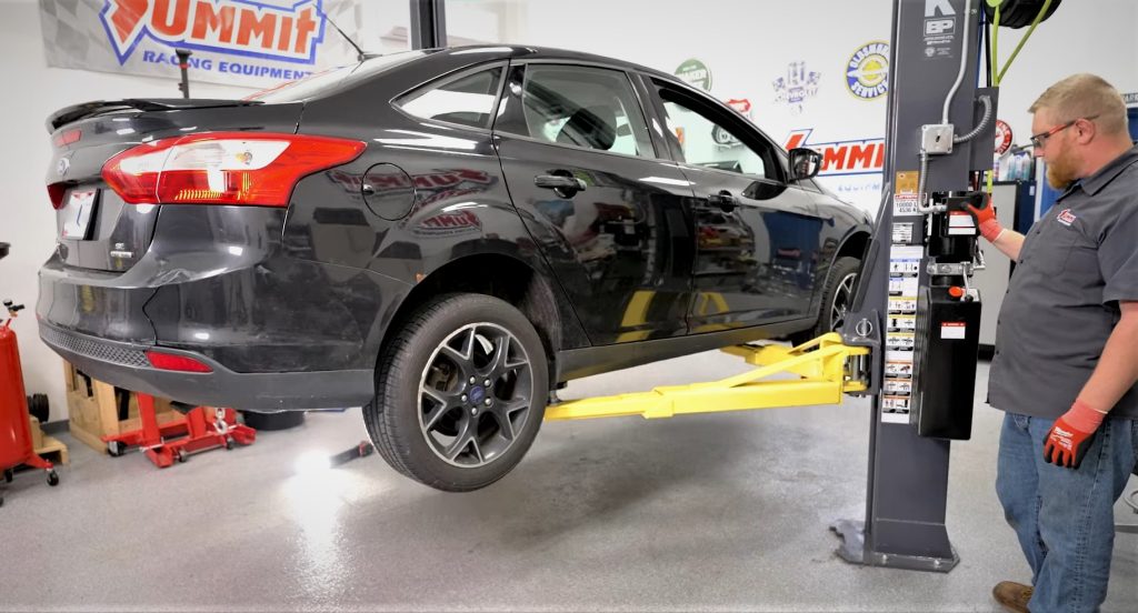 man using a 2 post vehicle lift to raise a ford car 2