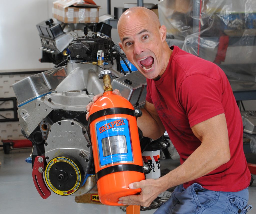 man holding a nitrous bottle near an engine