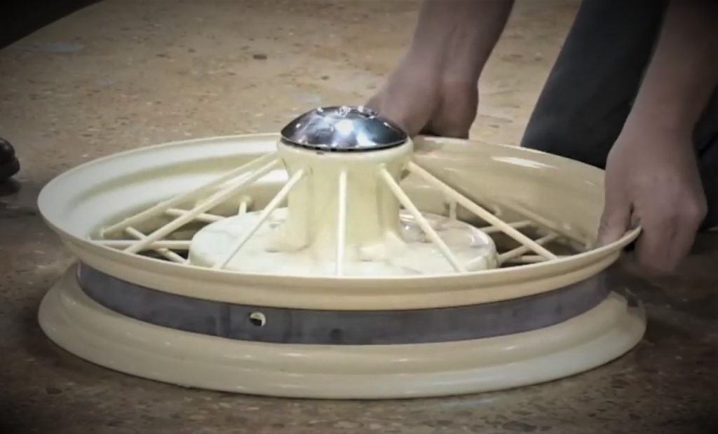man installing tire tube rim strip on a vintage spoked wheel
