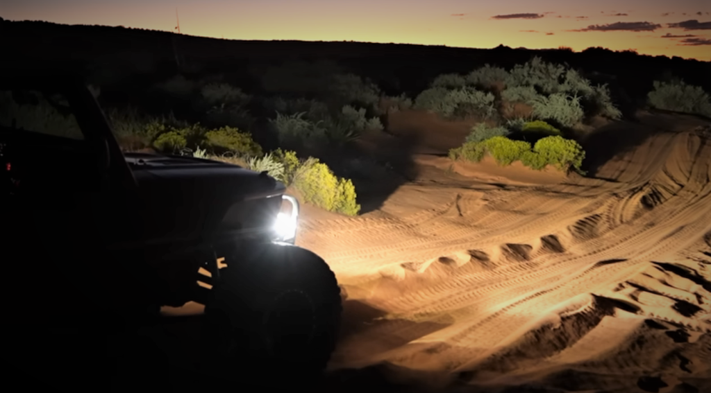 jeep lighting up a nighttime desert trail