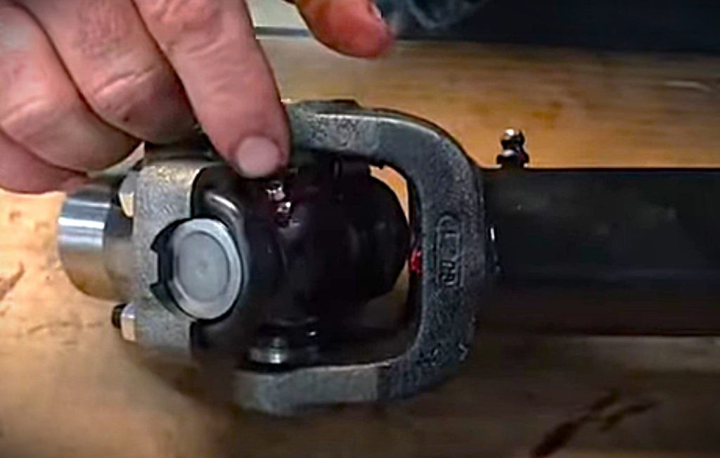 man pointing to a grease fitting on a u-joint