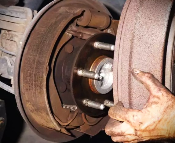 man removing brake drum from vehicle
