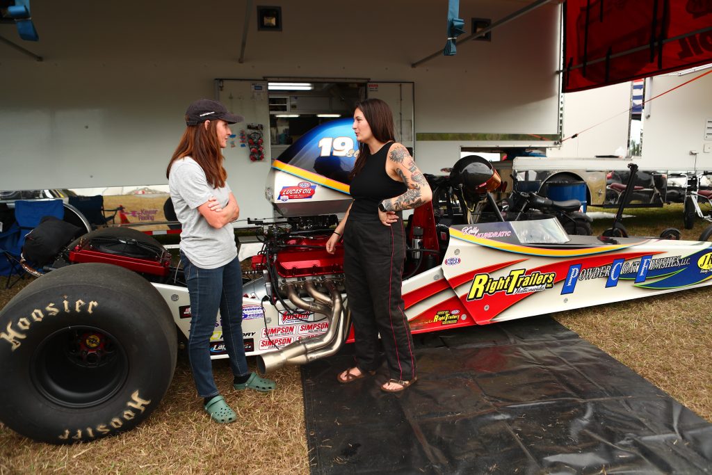 To racers talking next to dragster