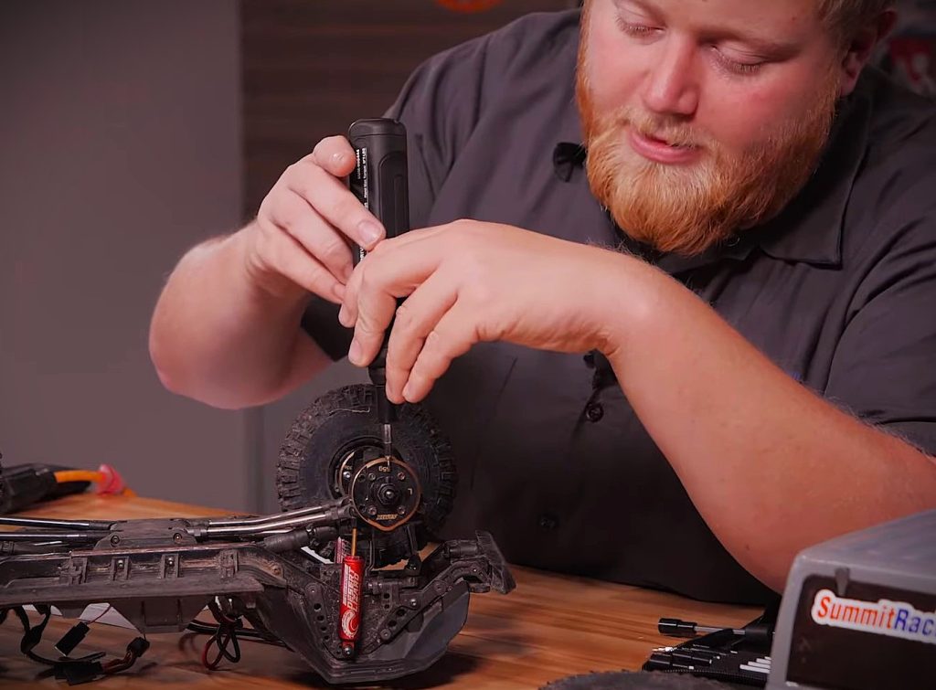 man using a power screwdriver on a small RC car