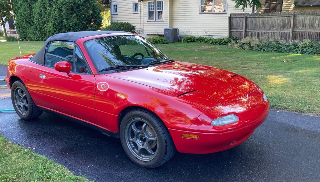front quarter shot of a red mazda miata NA in driveway