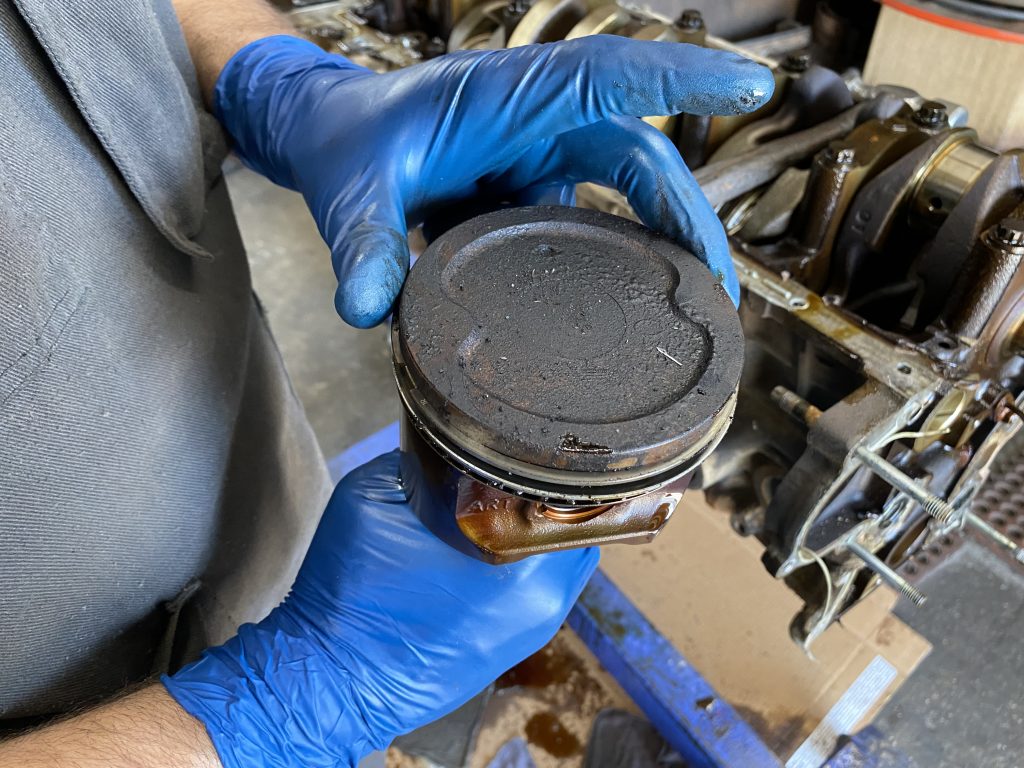 man holding a used engine piston