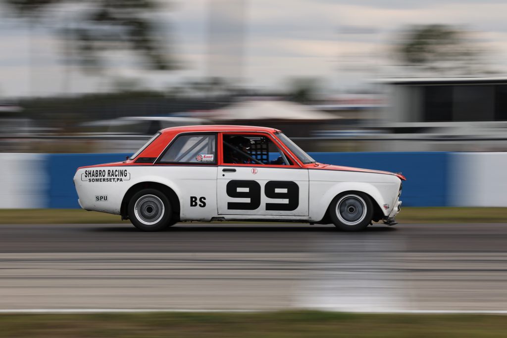 Side view of a vintage Datsun 510 race car on track