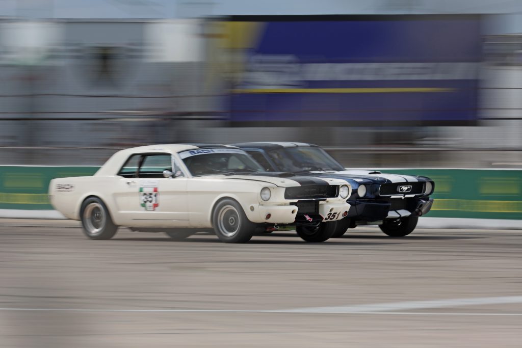a pair of first-gen Mustang race cars side by side on track