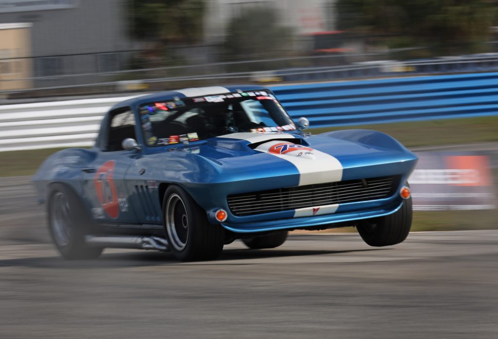 blue c2 Corvette Sting Ray race car lifting wheel on track
