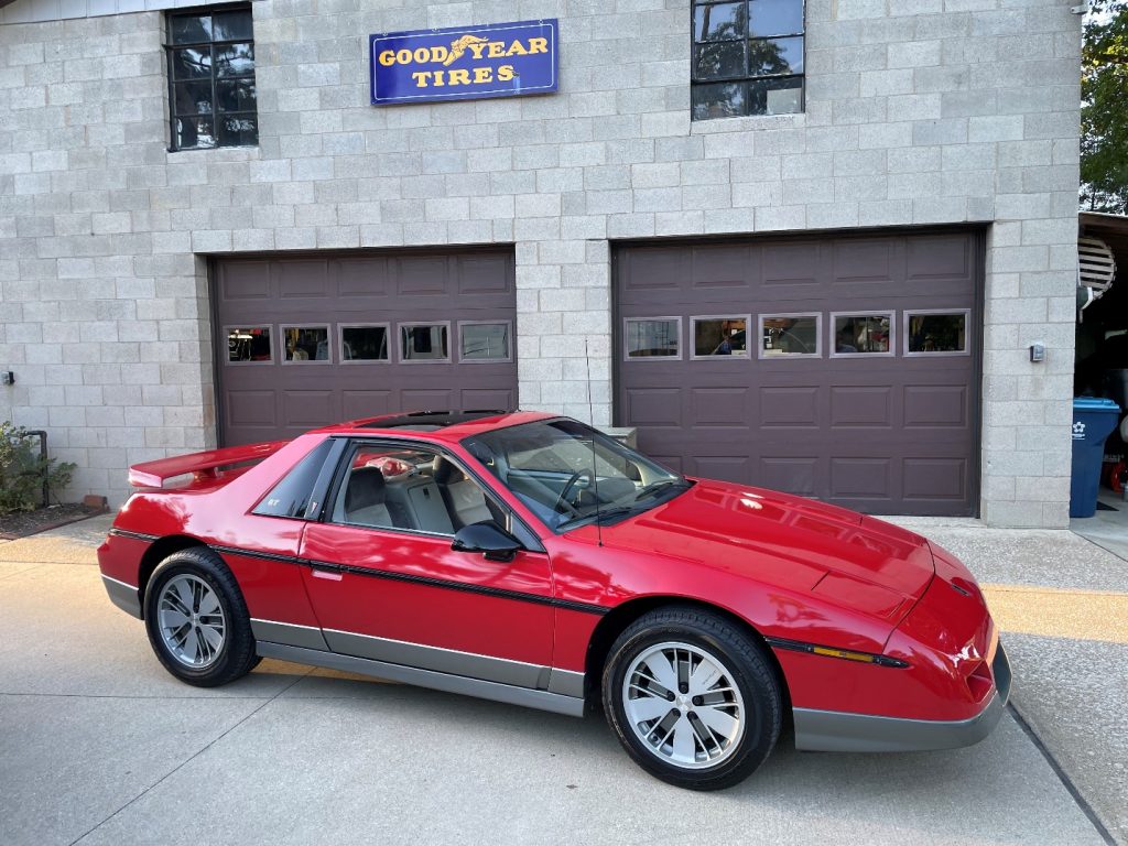 wide shot of a Pontiac fiero in front of a garage