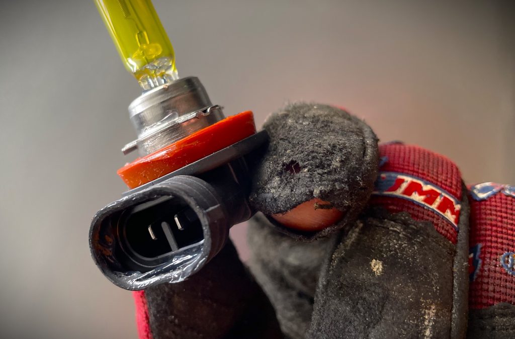 man holding a single automotive foglight bulb