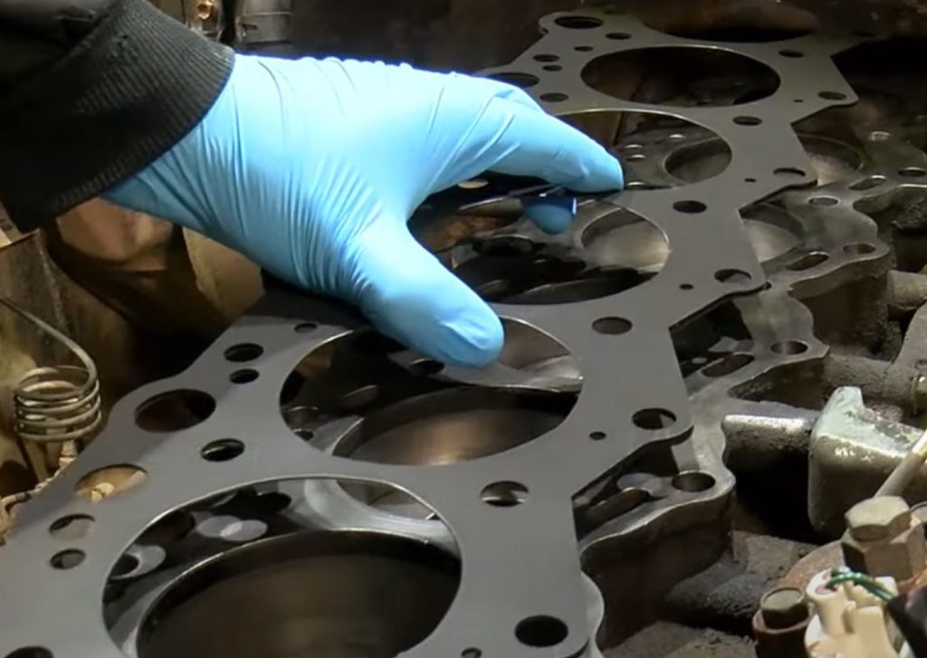 man placing a cylinder head gasket onto an engine