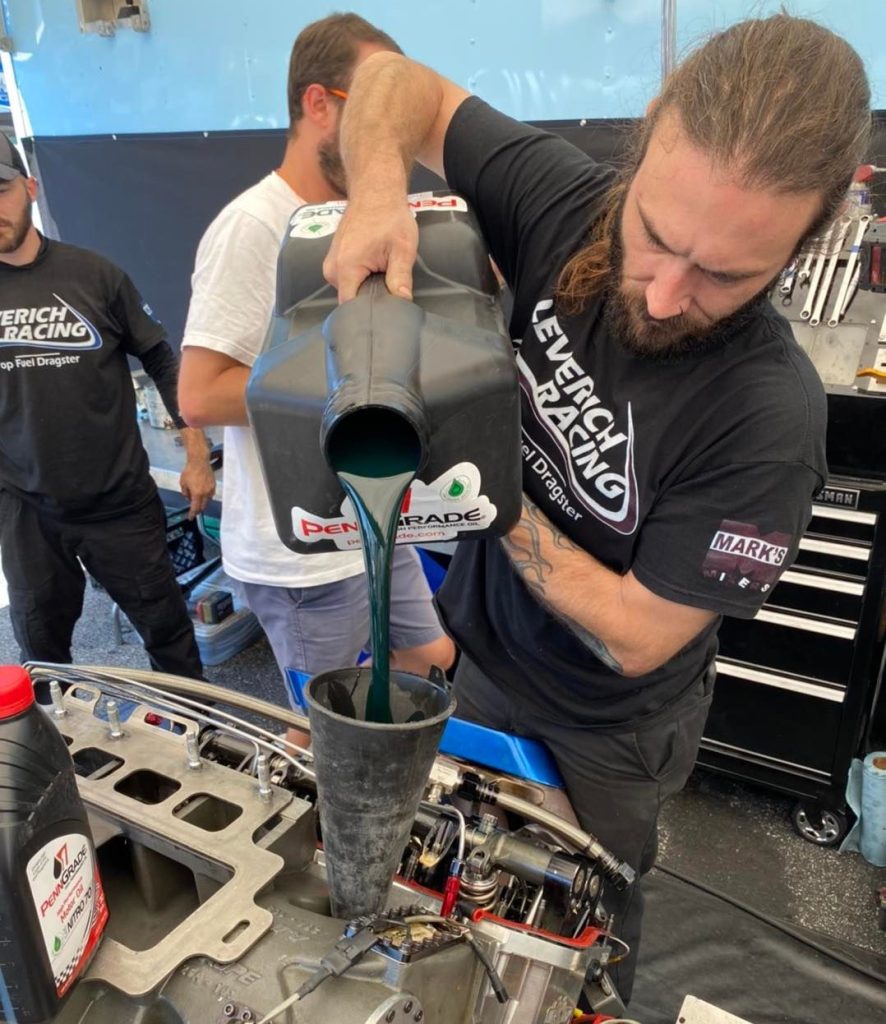 Man Filling dragster engine with PennGrade motor oil