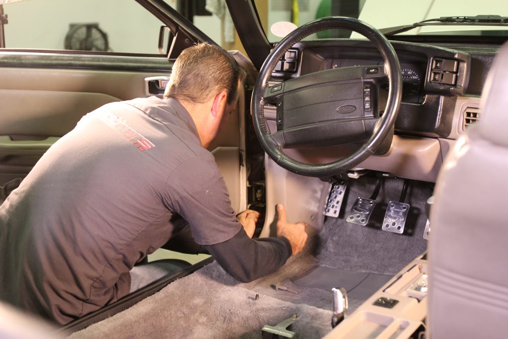 Man installing carpet in a car
