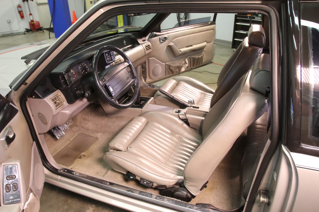 interior of an old foxbody mustang with dirty carpet