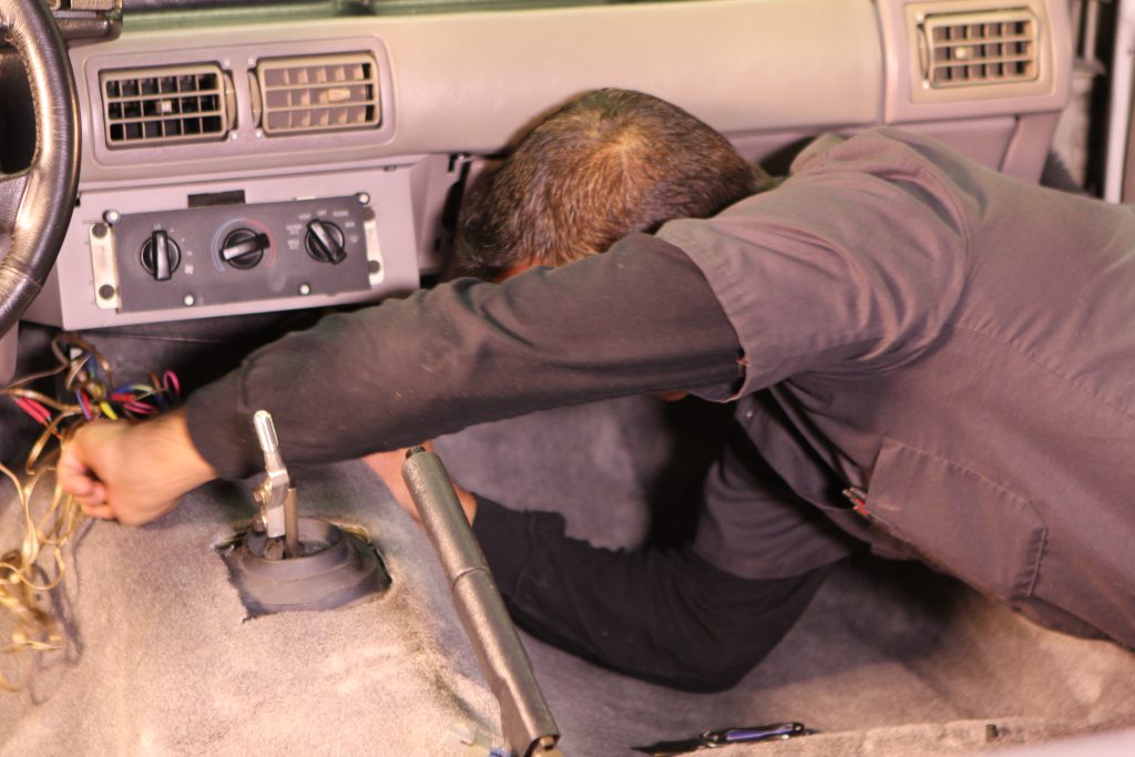 tucking new carpet in a car near firewall