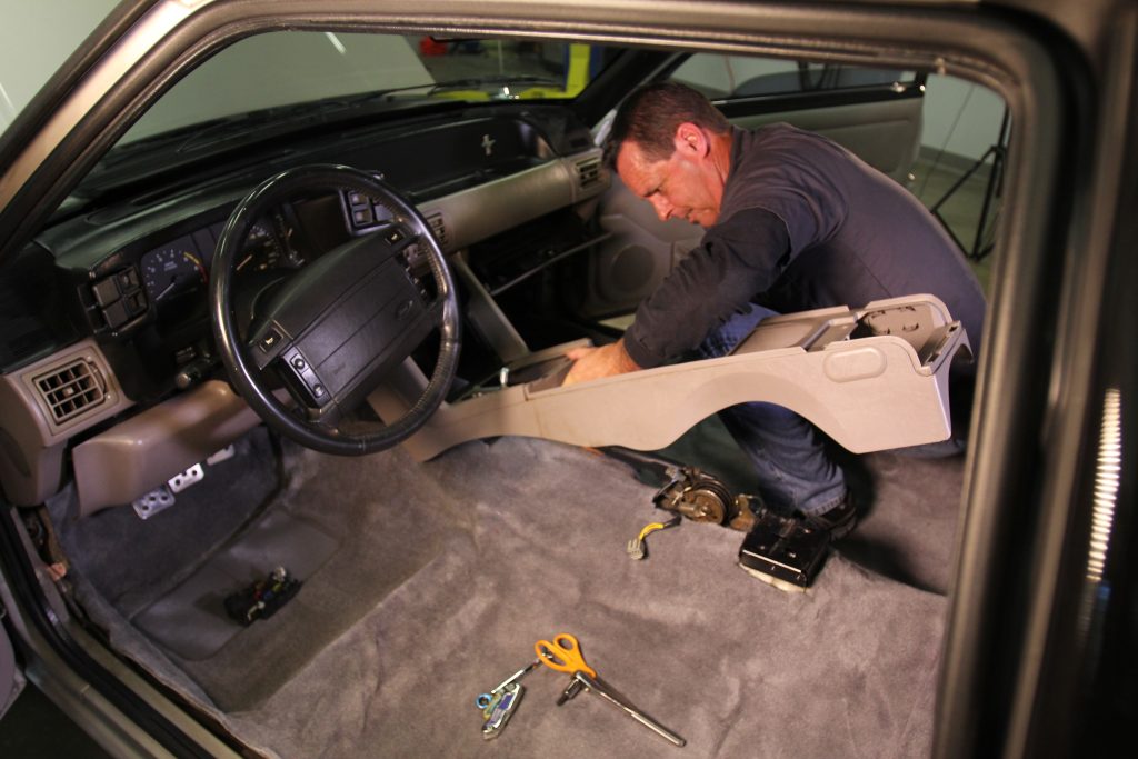 man installing a center console into a fox mustang